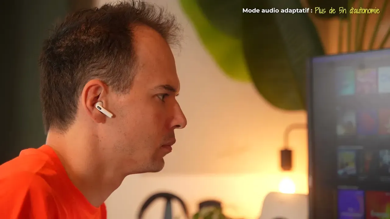 Kévin devant un écran, un écouteur AirPods 5 à l’oreille, en mode audio adaptatif