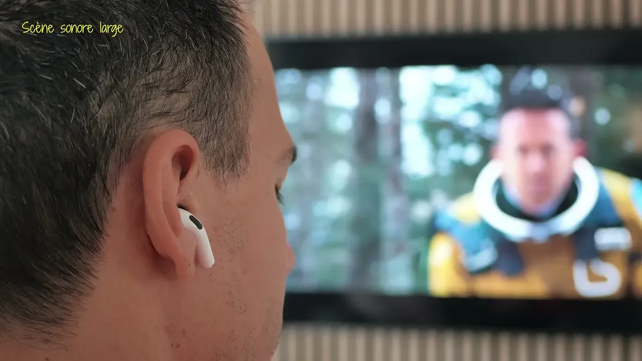 Kévin regarde un film sur un grand écran, un écouteur à l’oreille