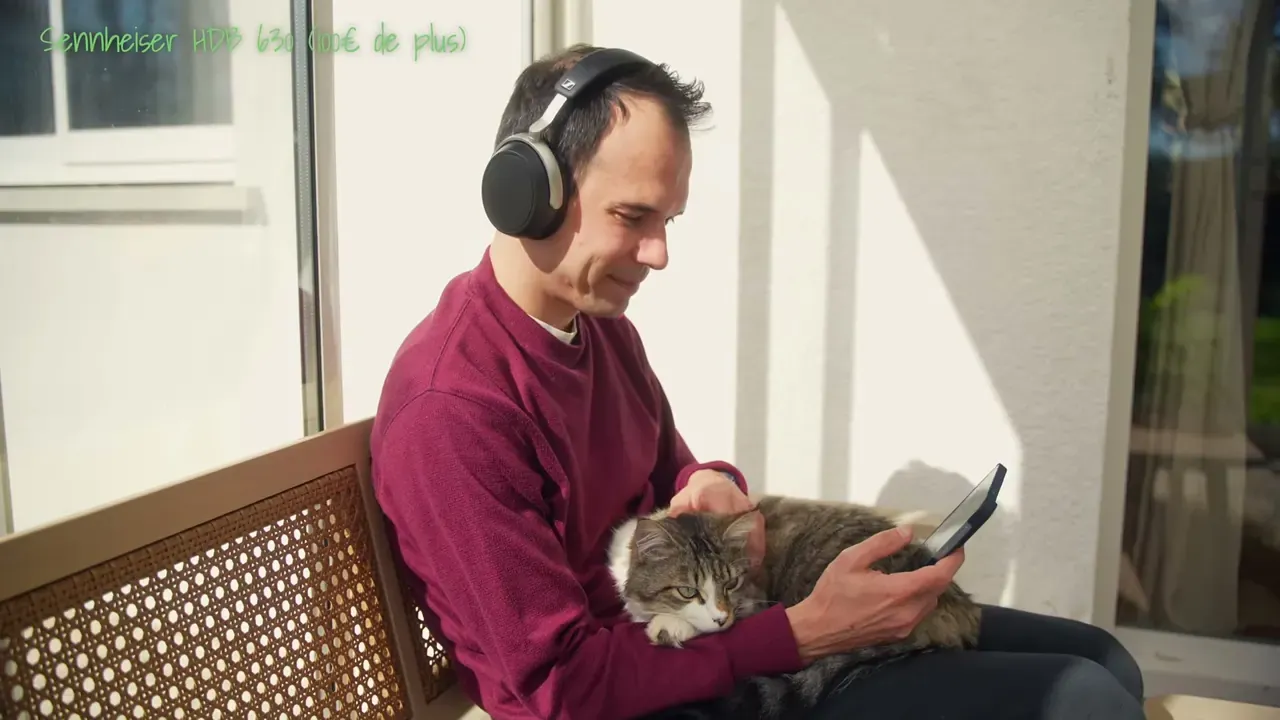 Kévin, le Sennheiser HDB 630 sur la tête, son chat sur les genoux, un téléphone à la main