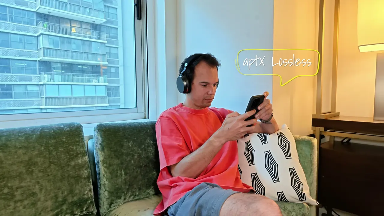 Kévin, le Momentum 5 sur la tête, regarde son téléphone dans un canapé